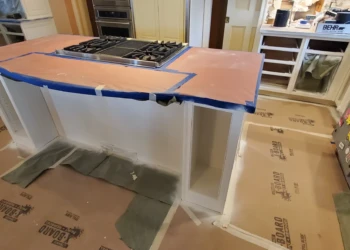Kitchen island with white cabinets under renovation showing covered countertops and protected flooring in Weston MA kitchen