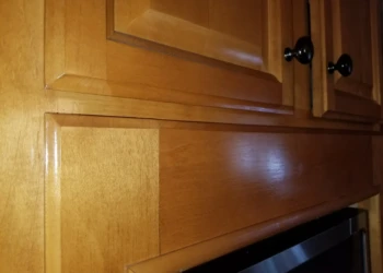 Close-up view of wooden kitchen cabinets showing finish and black knobs, typical of cabinet refinishing Wilmington project