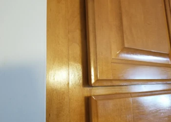 Close-up view of a wood cabinet door showing varnished finish and joinery details in Wilmington MA