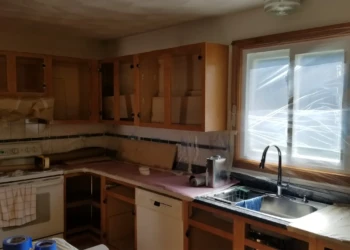 Kitchen cabinets and countertops covered in protective paper and plastic during cabinet refinishing prep in Wilmington MA