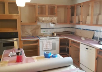 Kitchen cabinets in Wilmington MA with protective paper and tape during cabinet refinishing preparation