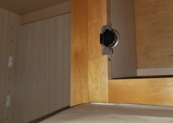 Close-up view of the edge of a wooden cabinet door showing hinge hardware and wood grain in Wilmington MA