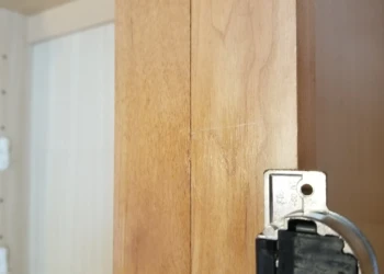Close-up view of a wooden cabinet edge showing surface wear and old finish before cabinet refinishing in Wilmington MA