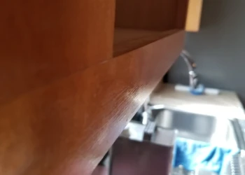 Close-up of a smooth wood cabinet door edge with rich finish, part of a kitchen setting in Wilmington MA