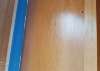 Close-up view of wooden cabinet surface with visible marks and uneven finish in Wilmington cabinet refinishing project