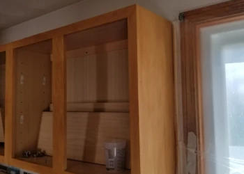 Unfinished wooden kitchen cabinets without doors installed, showing natural wood grain and construction details