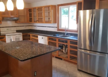 Kitchen with open wooden cabinets, granite countertops, and stainless steel refrigerator in Wilmington, MA