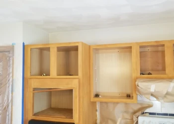Empty wooden upper kitchen cabinets prepared for cabinet refinishing in Wilmington Massachusetts