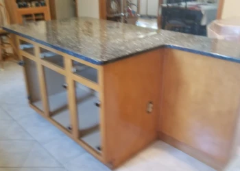 Wood kitchen cabinets with a dark granite countertop and tiled floor in a Wilmington home