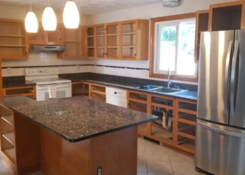 Kitchen cabinets in Wilmington MA with some doors removed, showing wood cabinet frames and granite countertops