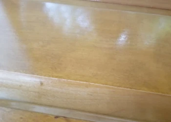 Close-up of a cabinet surface with visible uneven varnish and peeling finish