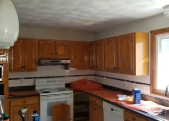 Glossy wooden kitchen cabinets with natural brown finish surrounding stove and sink area in Wilmington kitchen