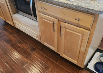 Partially stripped wooden kitchen cabinets and drawers under a granite countertop in Windham NH kitchen