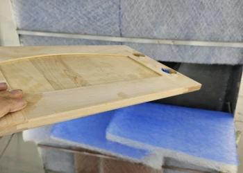 Hand holding a stripped and sanded cabinet door ready for refinishing in Windham NH cabinet refinishing project