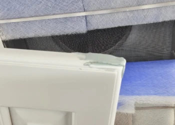 Close-up of a white cabinet door corner showing repaired damage during cabinet refinishing process in Windham NH