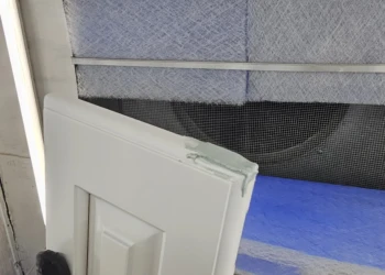 Close-up of gloved hand holding a repaired cabinet door corner during cabinet refinishing in Windham NH