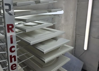 Primed white cabinet doors and drawer fronts drying on a rack in a workshop, part of cabinet refinishing in Windham NH