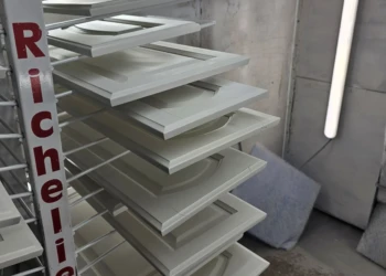 Cabinet doors and drawer fronts primed and drying on metal racks at a refinishing workshop in Windham NH
