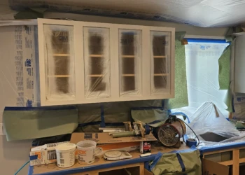 Primed kitchen cabinets in a workshop setting during cabinet refinishing project in Windham New Hampshire