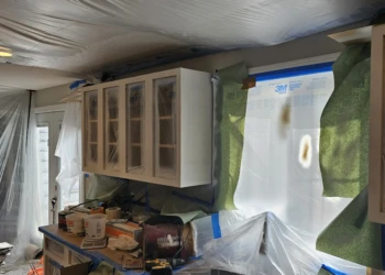 Kitchen cabinets primed and masked off during cabinet refinishing preparation in Windham NH