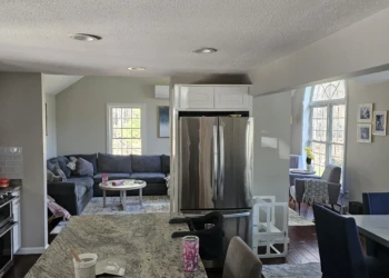 White refinished kitchen cabinets above stainless steel refrigerator in a Windham NH home