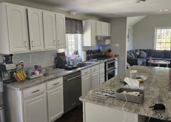 White refinished kitchen cabinets with a classic raised panel design and dark granite countertops in a Windham NH home