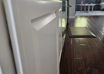 Close-up view of smooth white refinished kitchen cabinet doors with hardwood flooring in Windham NH