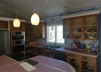 Kitchen cabinets being refinished with sanding and masking in progress.