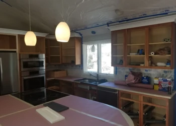 Kitchen cabinets being refinished with sanding and painting process.