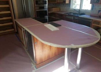 Kitchen island being refinished with protective covering and masking tape.