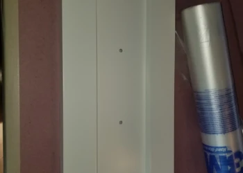Close-up of a cabinet door being refinished with a spray can nearby.