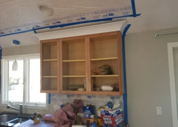 Cabinet refinishing service with new wood cabinet doors and masking tape.