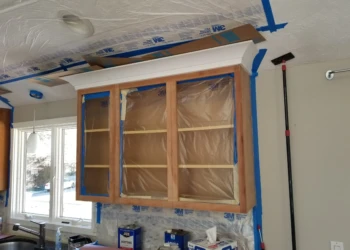 Cabinet refinishing service with cabinets covered in protective paper and masking tape.