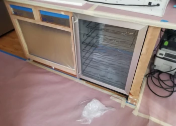 Cabinet refinishing with sanding and masking in progress.