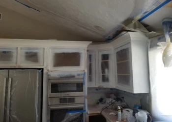 Kitchen cabinets being refinished with masking tape and primer.
