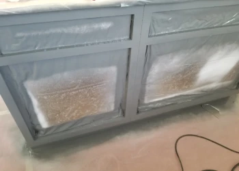 Cabinet refinishing with paint and masking tape on kitchen cabinets.
