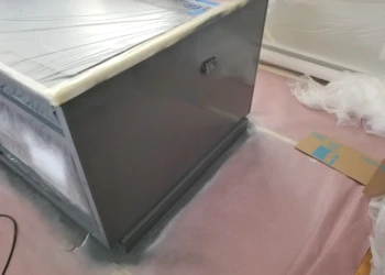 Kitchen cabinet being refinished with spray paint and masking tape.