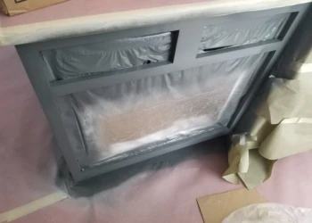 Cabinet refinishing process with masking and plastic covering.