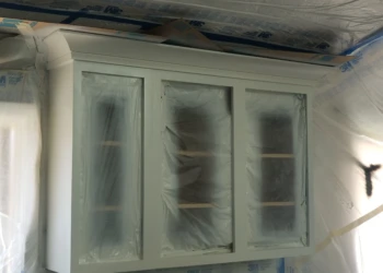 Cabinet refinishing in progress with masking and sanding visible.