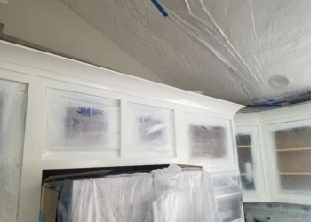 Cabinet refinishing with masking and painting in progress.