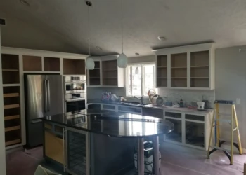 Kitchen cabinets being refinished with new paint and hardware.