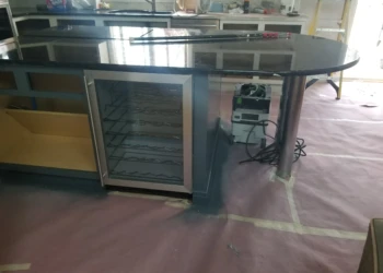 Refinishing cabinets with a spray gun in a workshop setting.