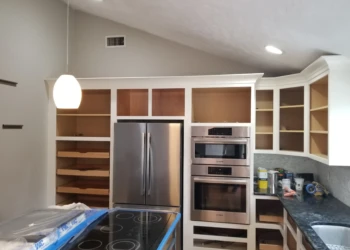 Kitchen cabinets being refinished with paint and new hardware.