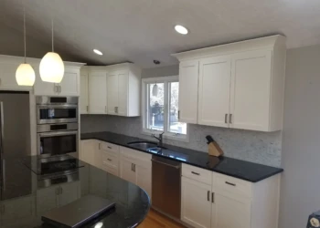 Kitchen cabinets being refinished with white paint and new hardware.