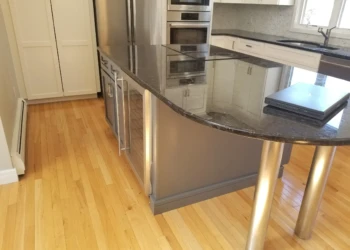 Kitchen cabinet refinishing with a dark granite countertop and stainless steel appliances.