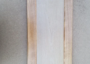 Wood cabinet door being sanded and prepared for refinishing.