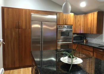 Kitchen cabinets being refinished with a dark stain in a modern kitchen.