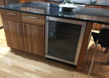 Refinished wooden cabinets next to a wine cooler in a kitchen.