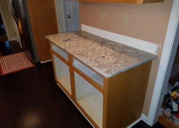 Empty kitchen base cabinets without doors under a granite countertop ready for cabinet refinishing in Pelham NH