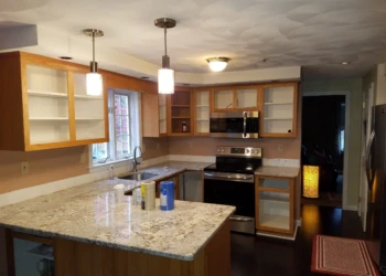 Kitchen cabinets in Pelham NH during preparation for cabinet refinishing with doors removed and surfaces exposed
